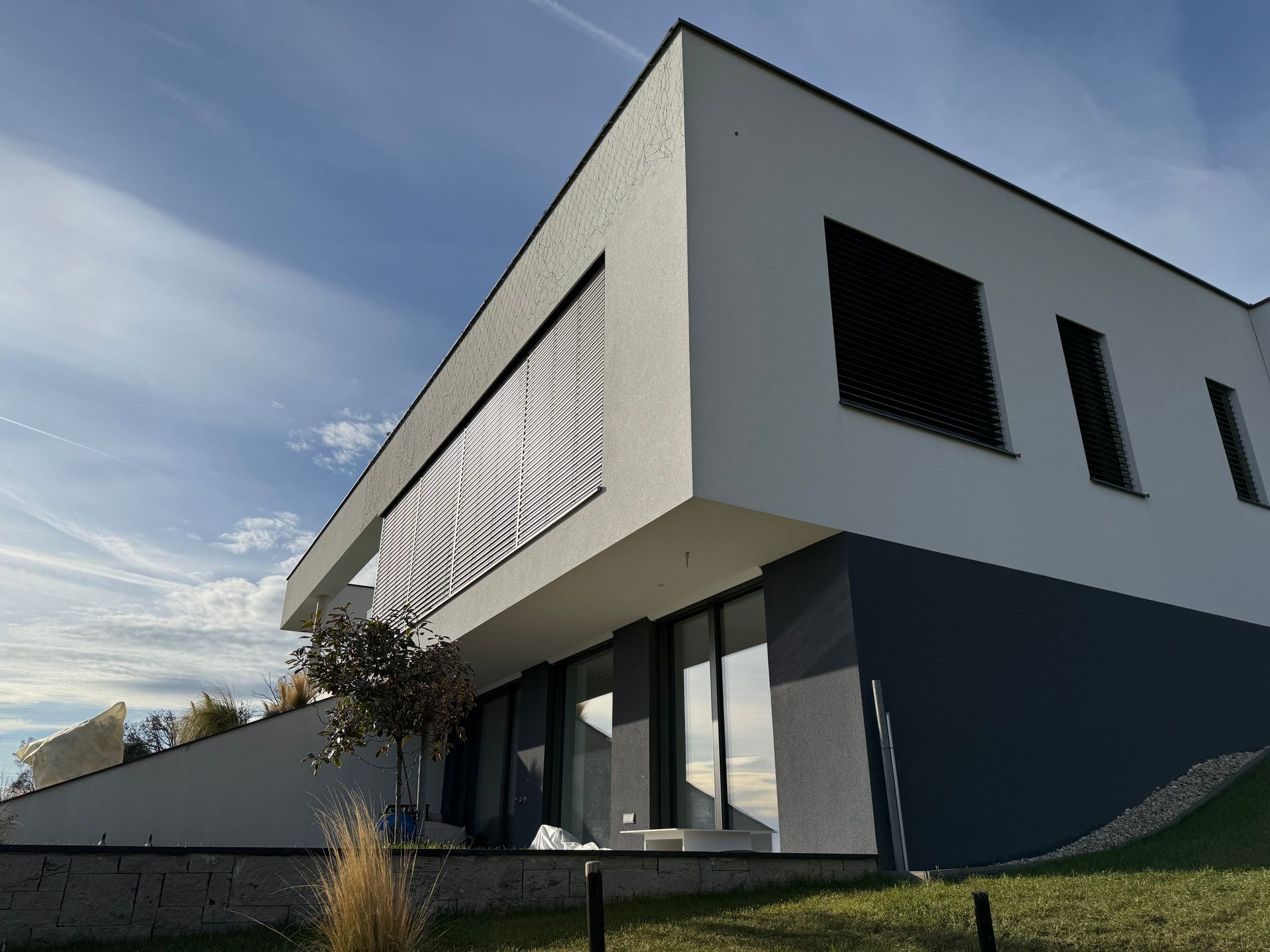 Auf einem Hügel steht ein modernes Haus mit vielen Fenstern.