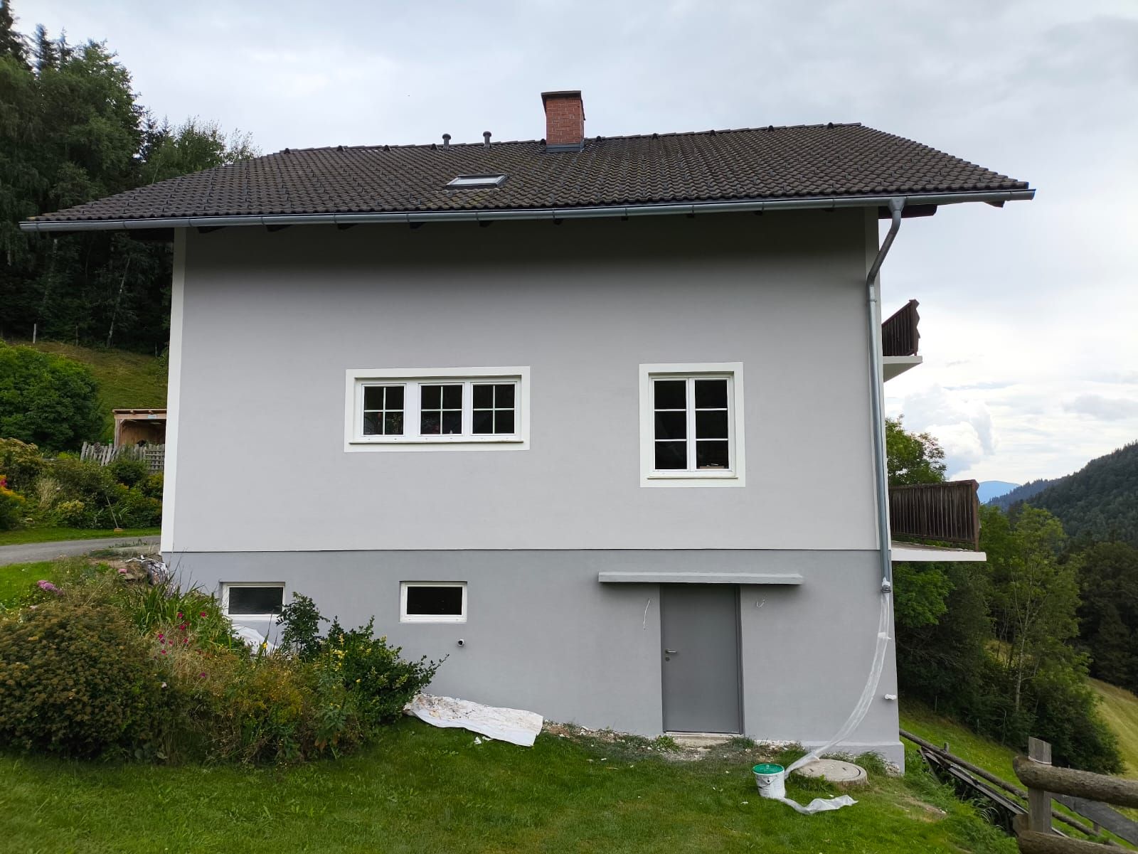 Auf einem grasbewachsenen Hügel steht ein weißes Haus mit einem Schornstein auf dem Dach.
