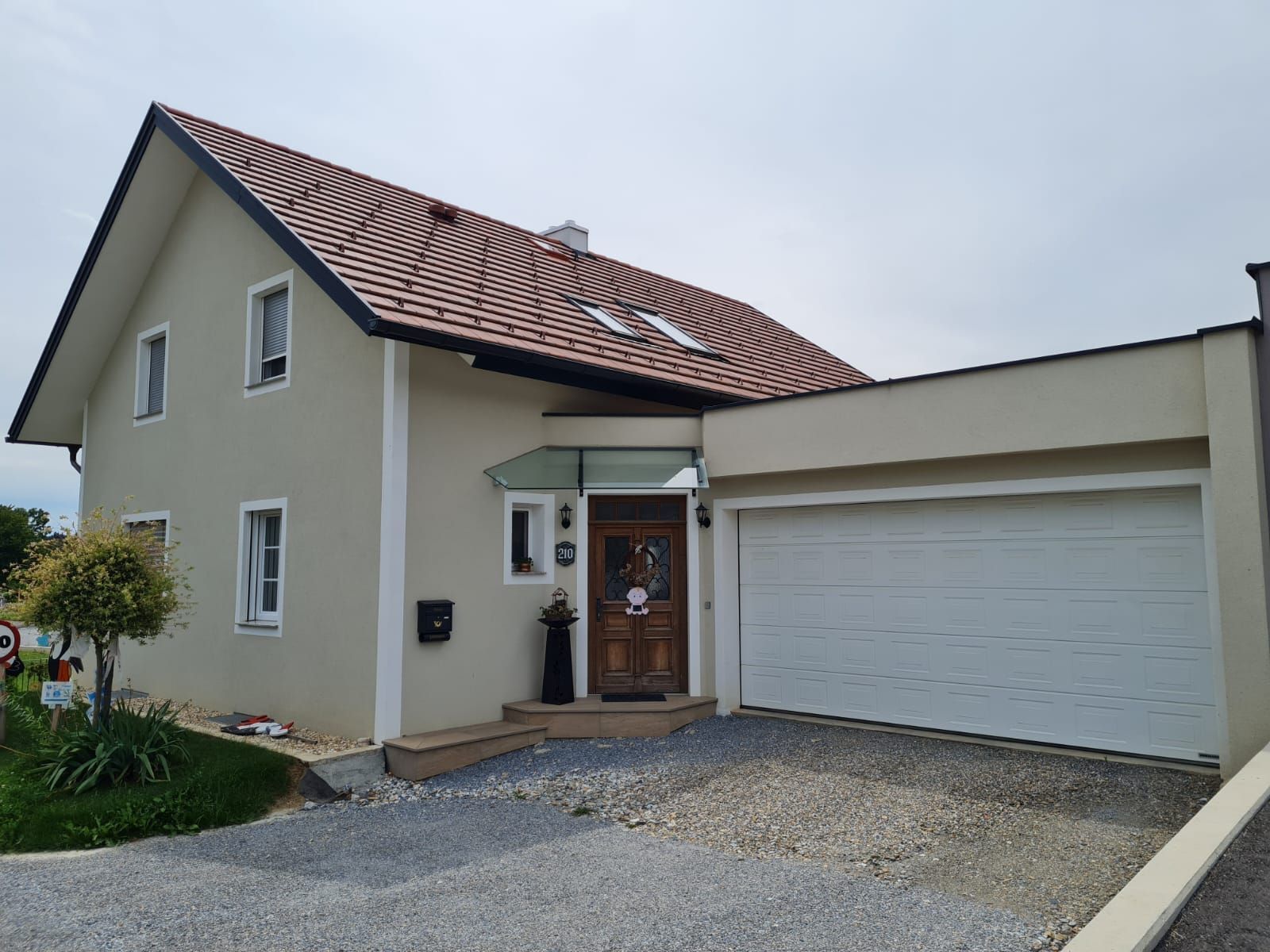 Ein weißes Haus mit einem braunen Dach und einem weißen Garagentor