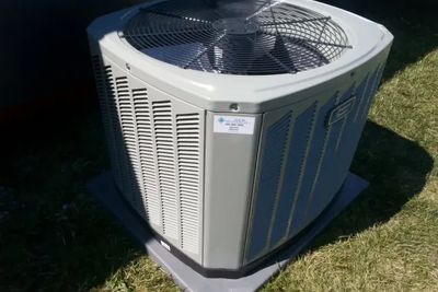 A large air conditioner is sitting on top of a grass covered field.