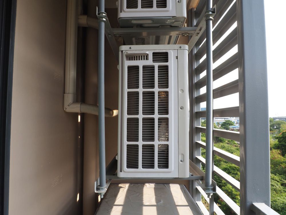 Two Heat Pumps Are Hanging from The Side of A Building on A Balcony — Sunworks Eco Plumbing In Torquay, VIC