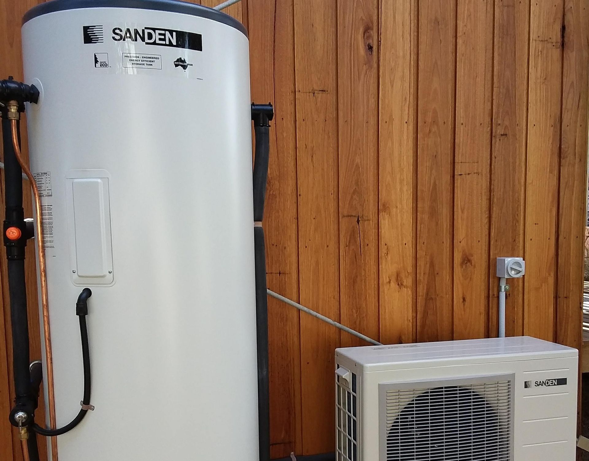 Sanden heat pump hot water system installed against timber fence, Geelong.