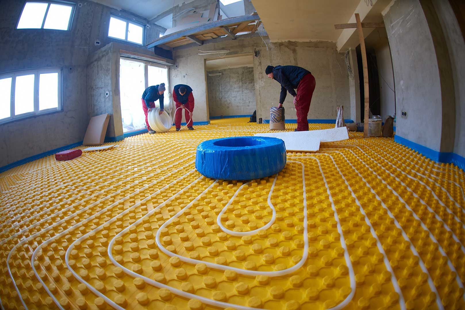 A Group of Men Are Working on A Yellow Underfloor Heating System — Sunworks Eco Plumbing In Altona, VIC