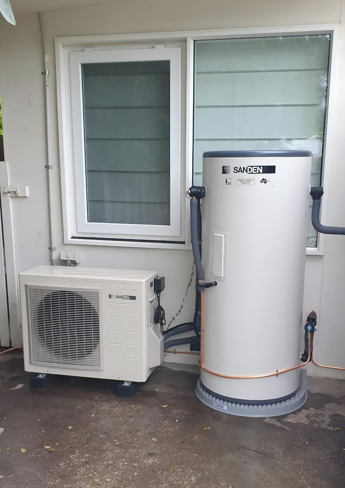 Sanden heat pump hot water tank and outdoor compressor unit installed beside a house window in Geelong