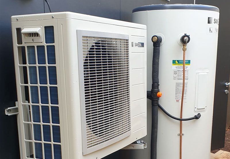A Heat Pump and A Water Heater Are Sitting Next to Each Other — Sunworks Eco Plumbing In Torquay, VIC