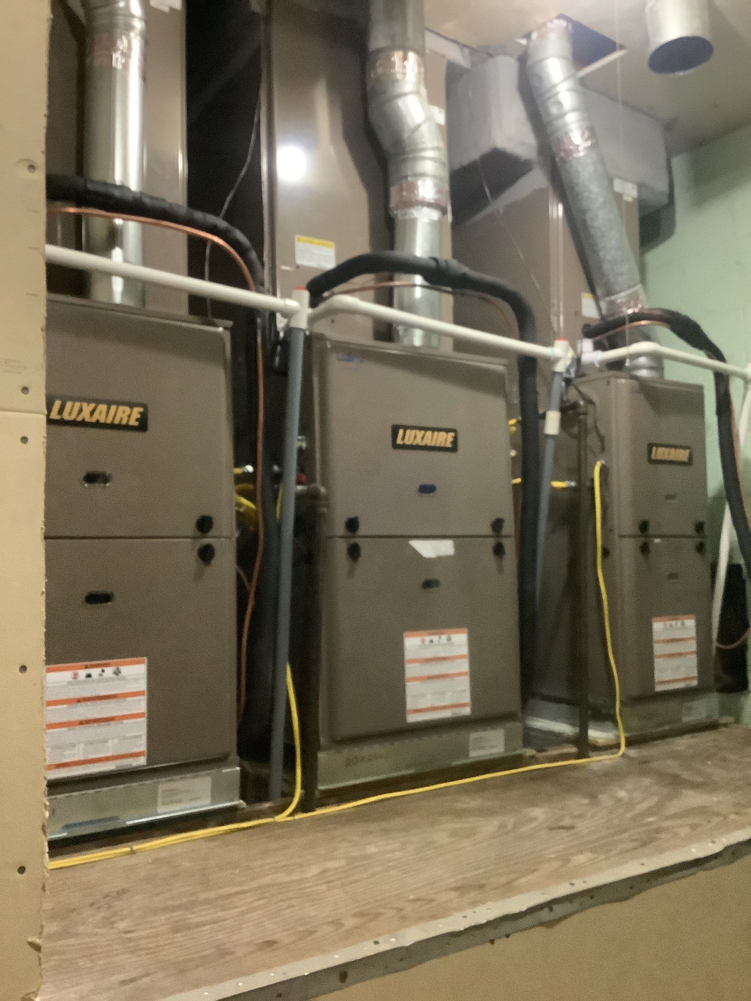 Three luxaire air conditioners are lined up in a room