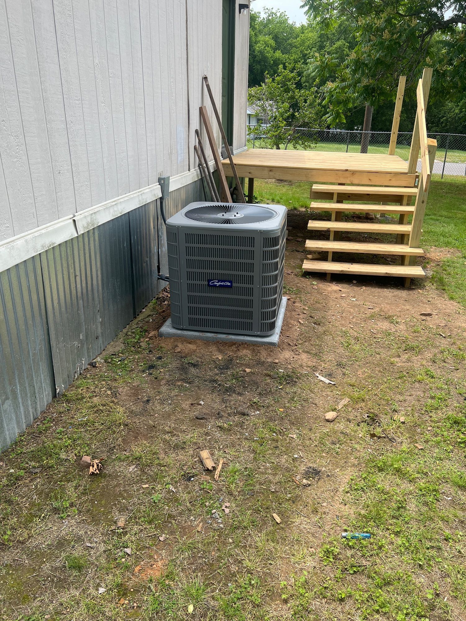 A mobile home with a deck and stairs in the backyard.