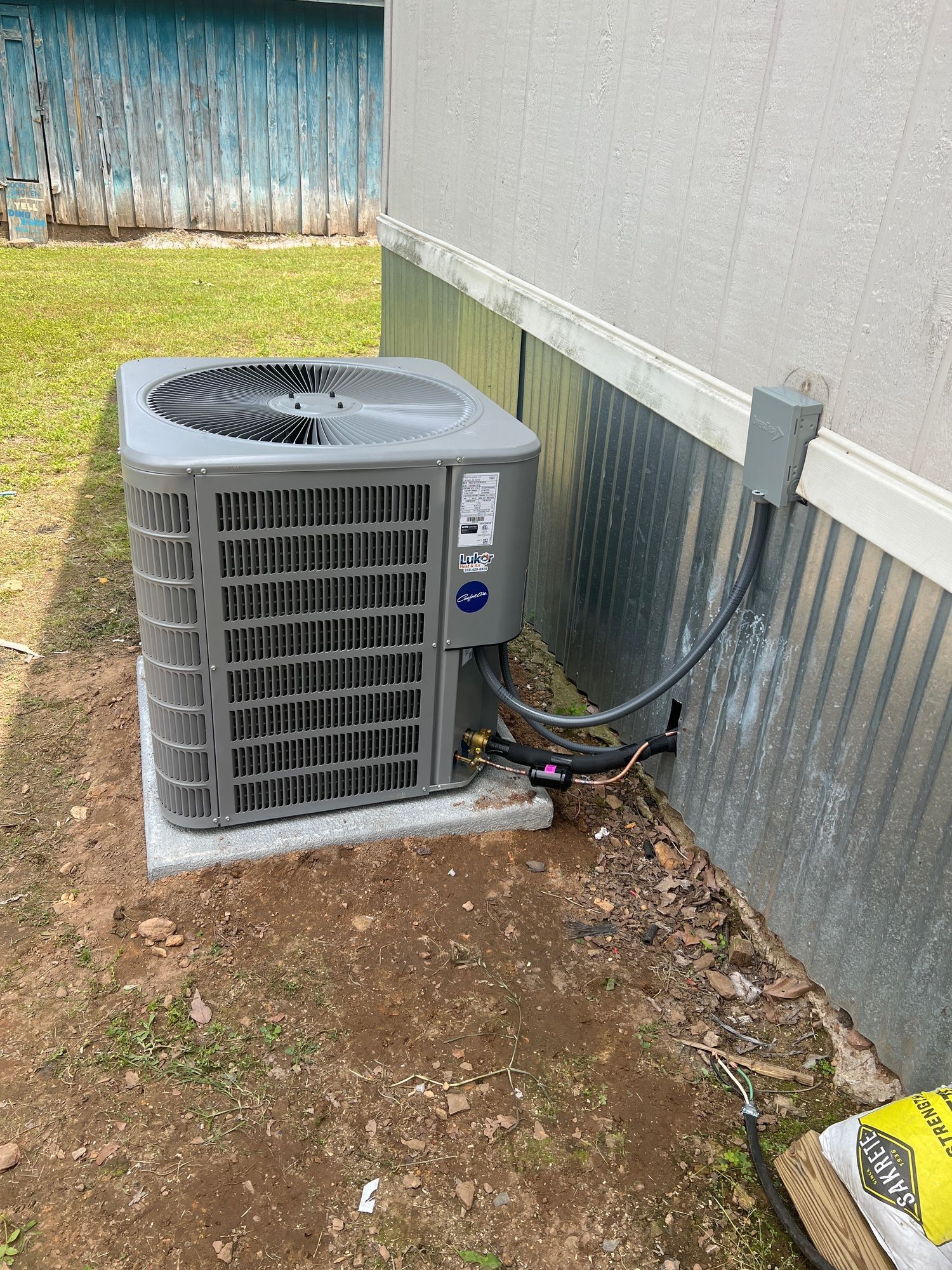 An air conditioner is sitting on the ground next to a wall.