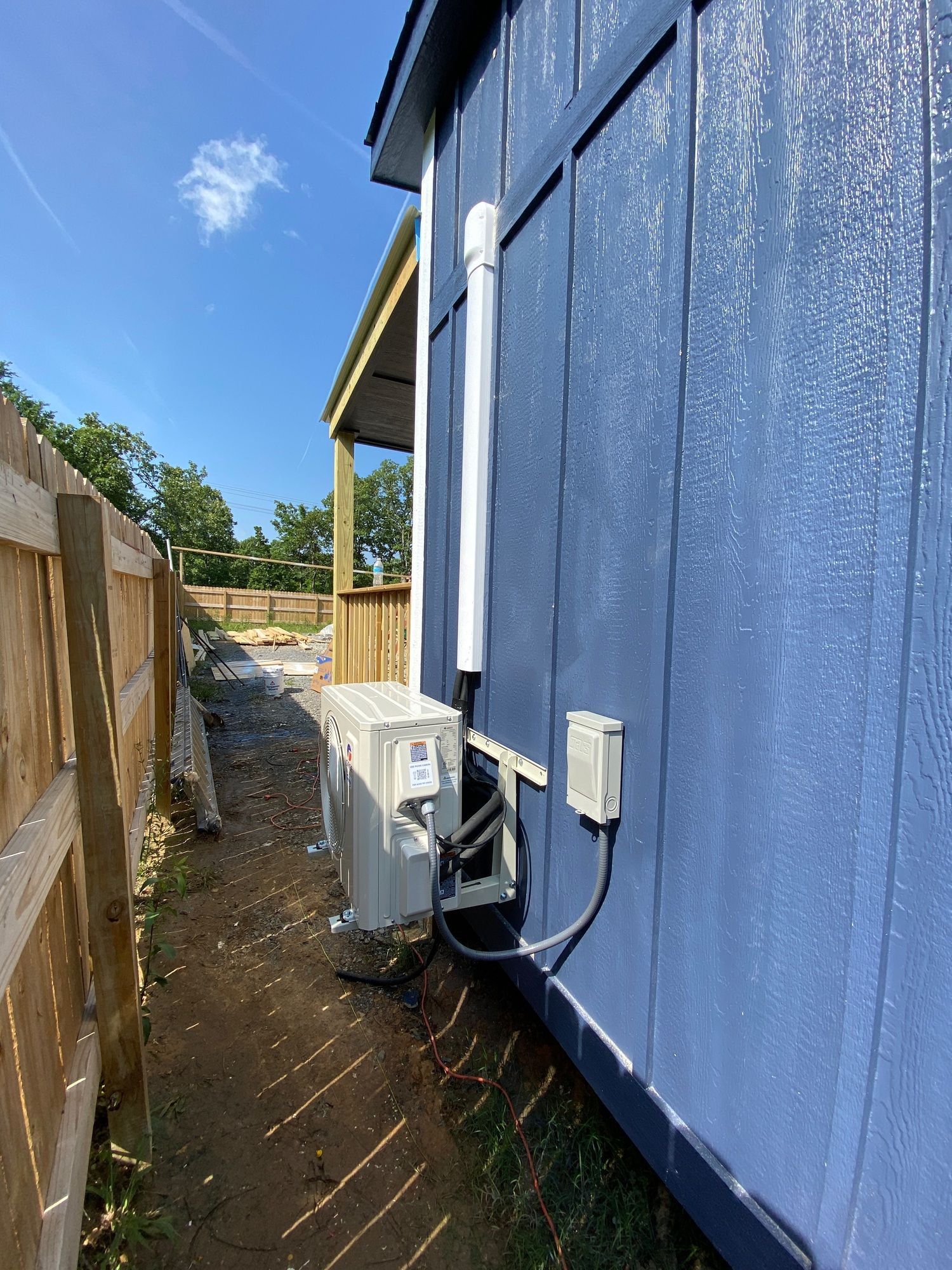 A blue house with a white pipe attached to the side of it.