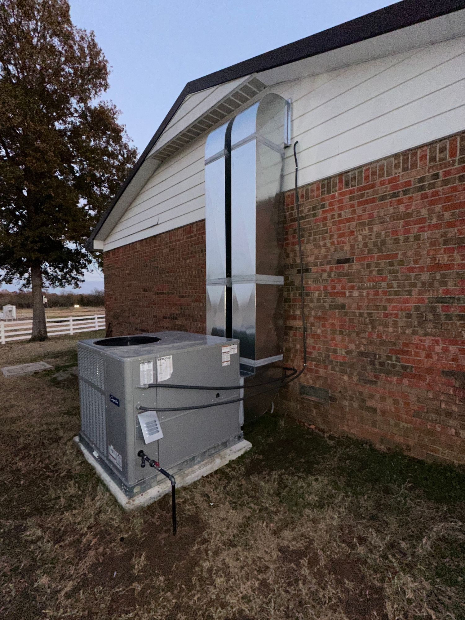 A large air conditioner is sitting on the side of a brick building.
