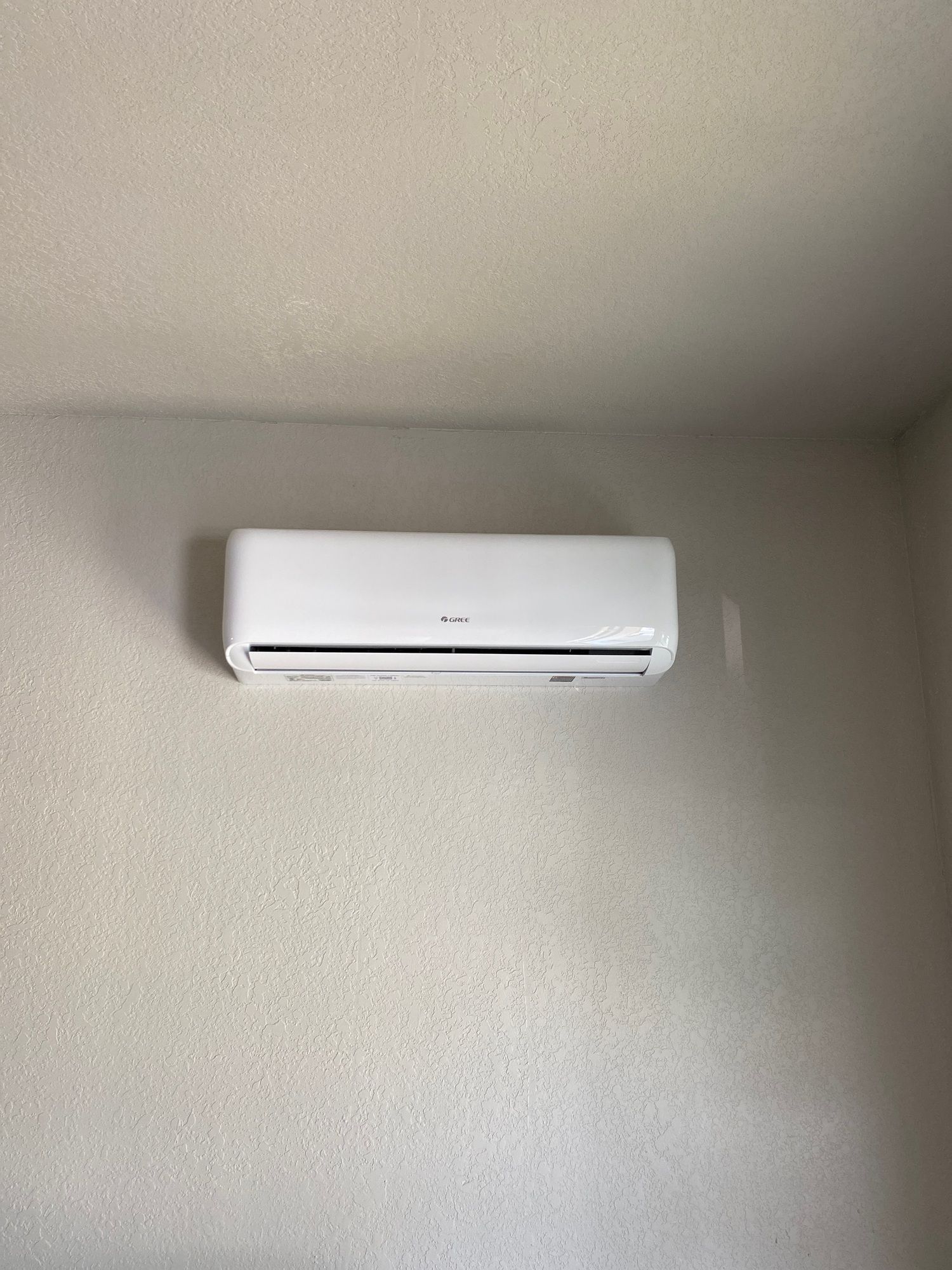 A white air conditioner is hanging on a wall in a room.