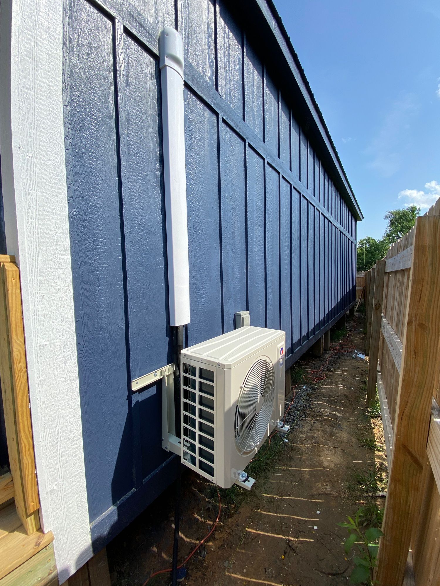 A white air conditioner is mounted on the side of a blue building.