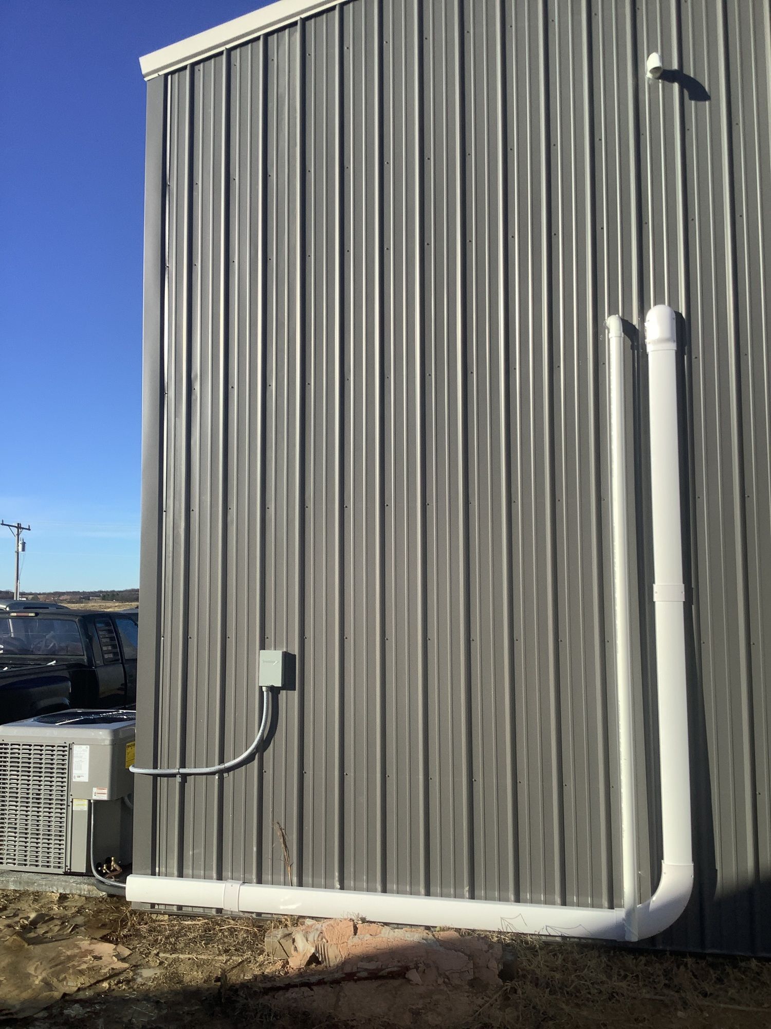 A gray building with a white pipe attached to the side of it.