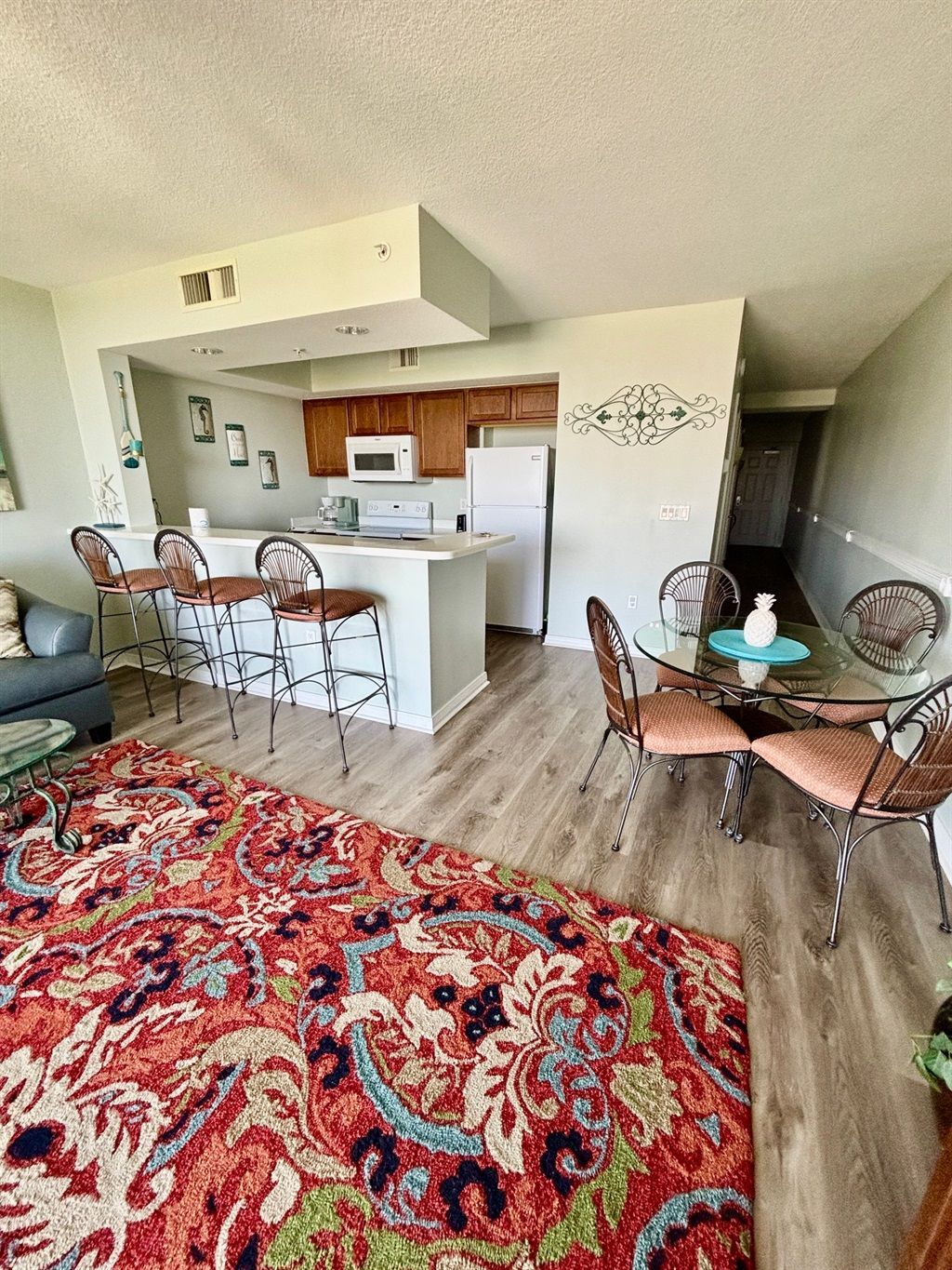 Cozy living room with wall-mounted TV, white cabinet, blue chair, and colorful patterned rug