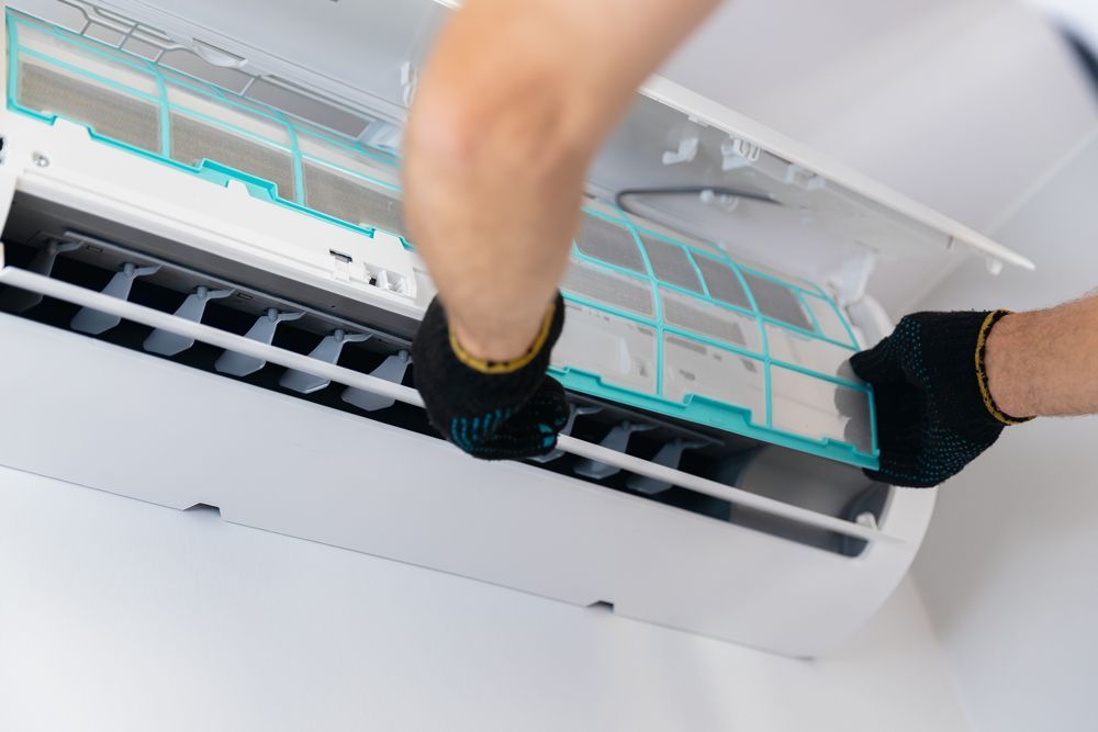 A person is cleaning the filter of an air conditioner.