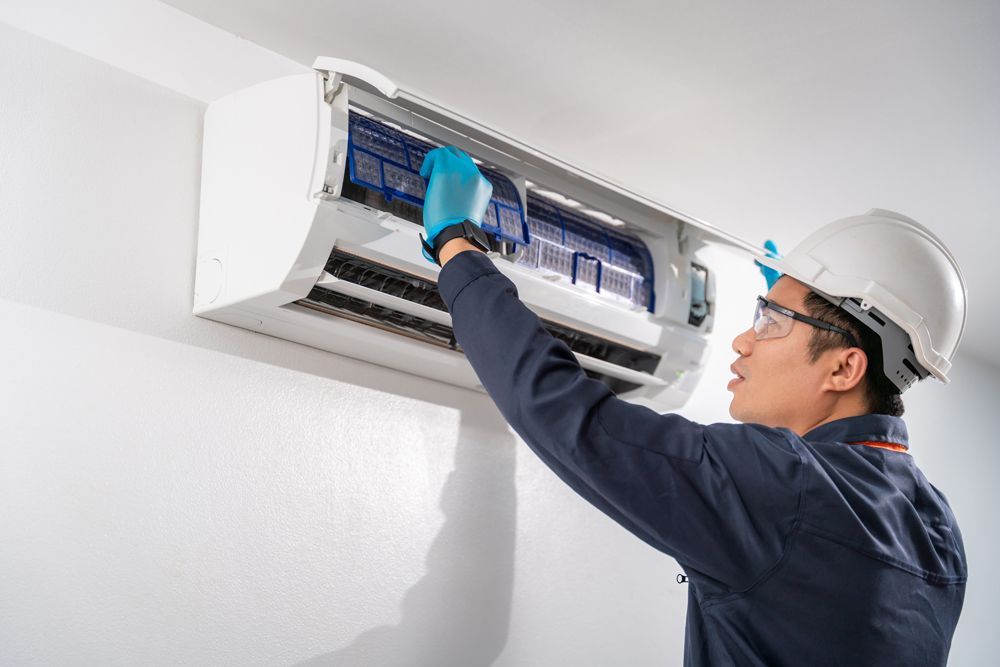 A man is working on an air conditioner in a room.