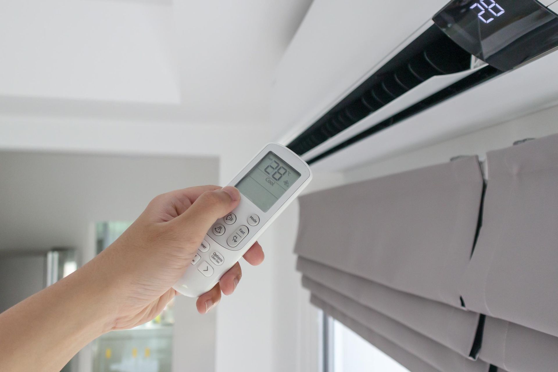 A person is using a remote control to turn on an air conditioner.