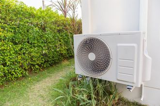A white air conditioner is sitting on the side of a building.