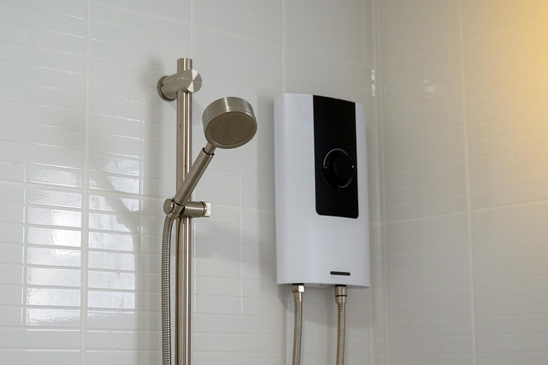 There is a shower head and a water heater in the bathroom.