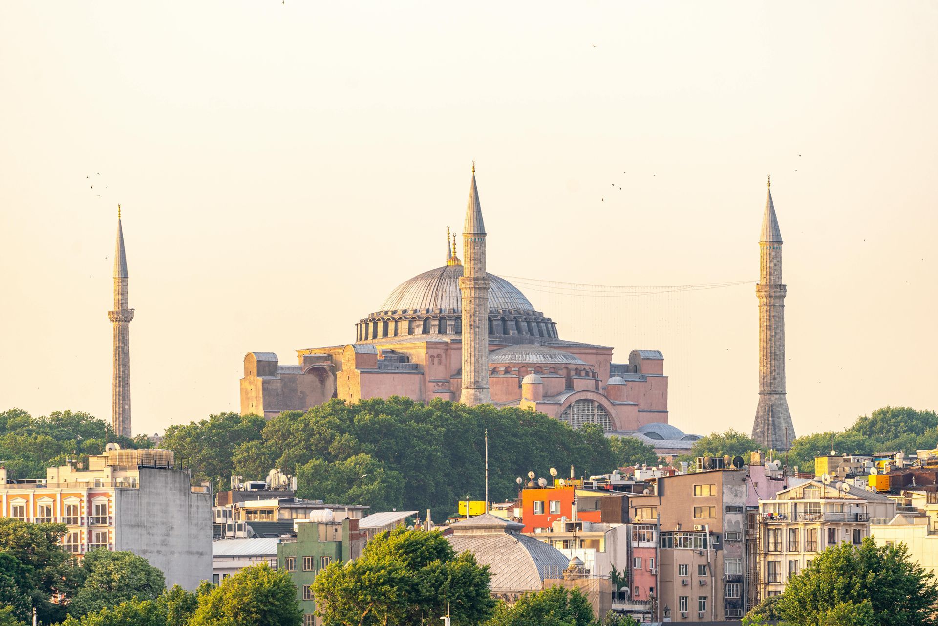 Historic mosque with a large central dome and minarets rising above a city skyline at sunset