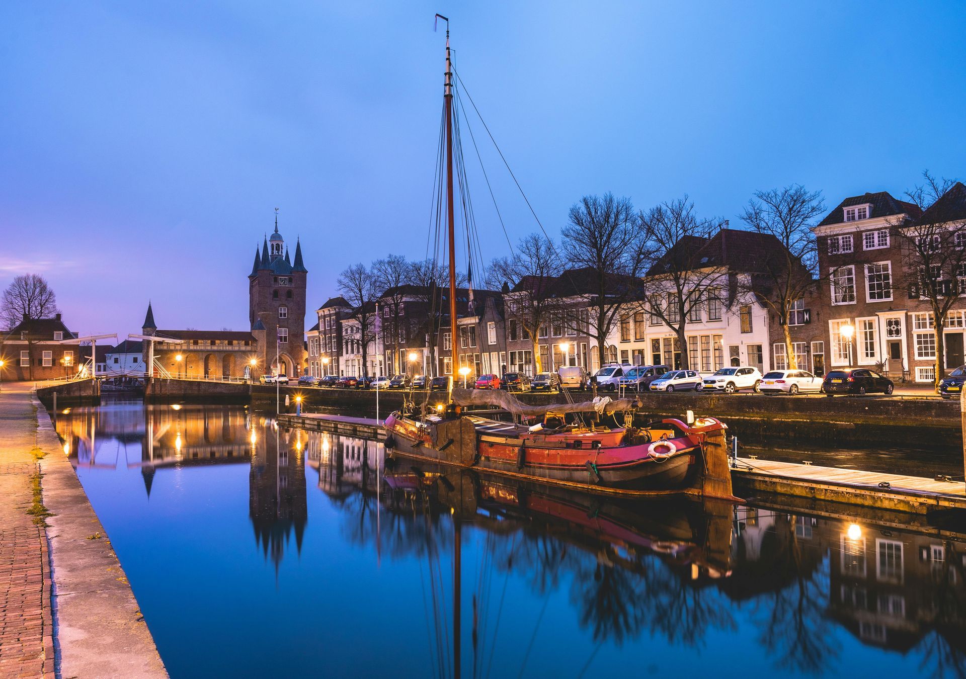Twilight canal scene with lit boats, historic buildings, and reflections on calm water