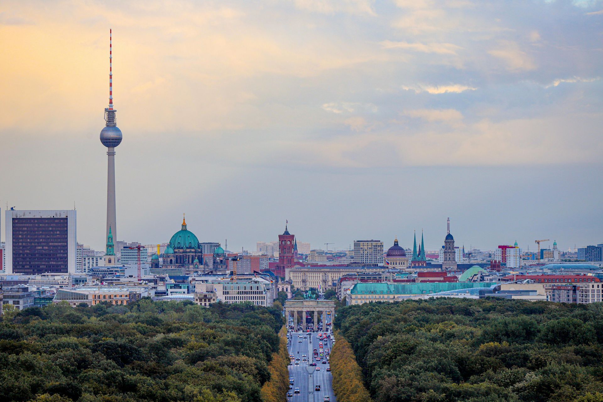 Berlin skyline at dusk with the TV Tower and the Berlin Cathedral above a tree-lined boulevard