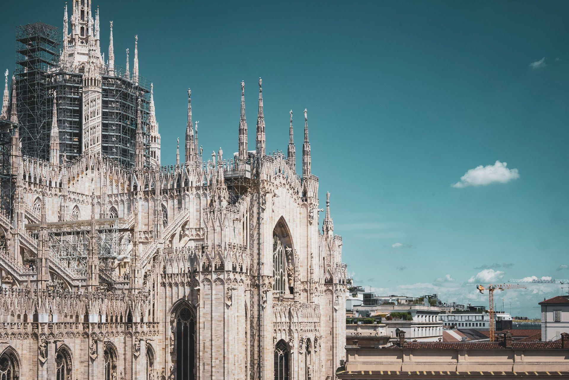 Gothic cathedral façade with ornate spires under a blue sky with a small cloud