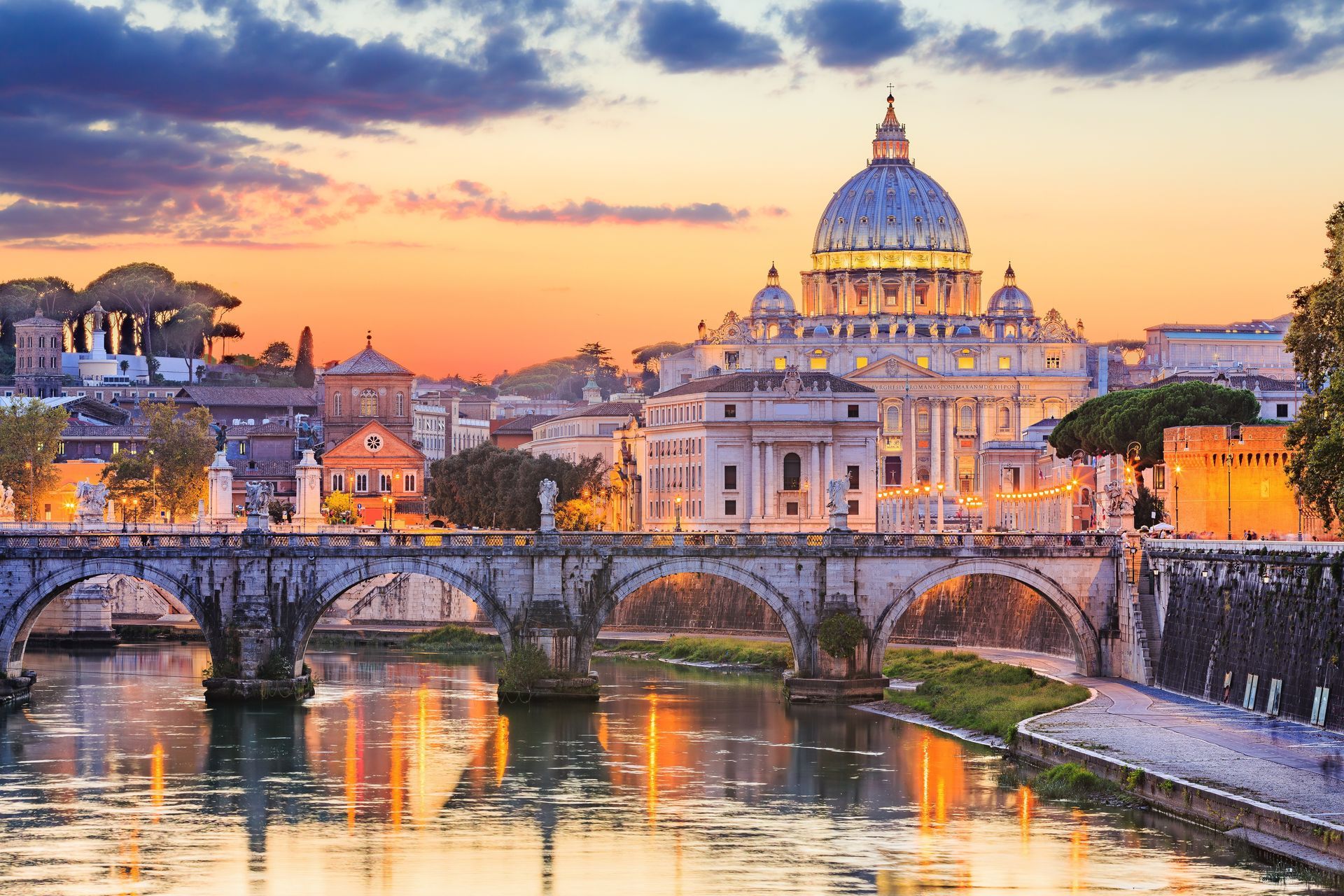 St. Peter’s Basilica and bridge over the Tiber at sunset, with colorful sky and reflections in the water