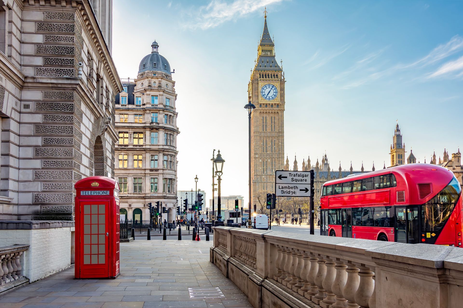 Red phone booth and red double-decker bus near Big Ben in London street scene