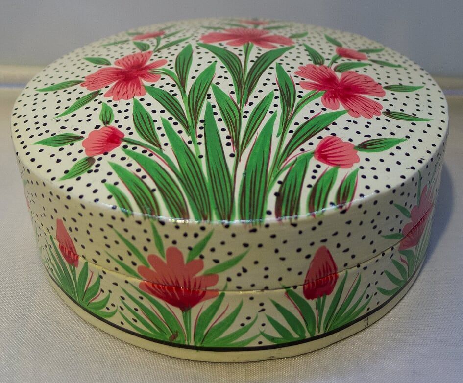 Round, white jewelry box with pink floral design and black polka dots.