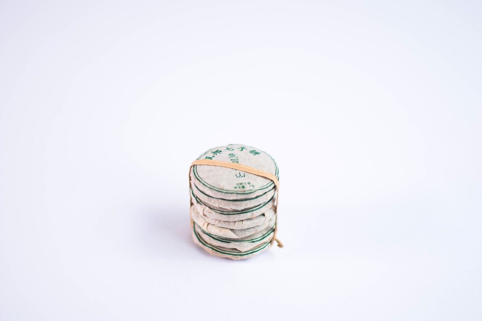 Stack of white circles with green text, held together by a rubber band, on a white background.