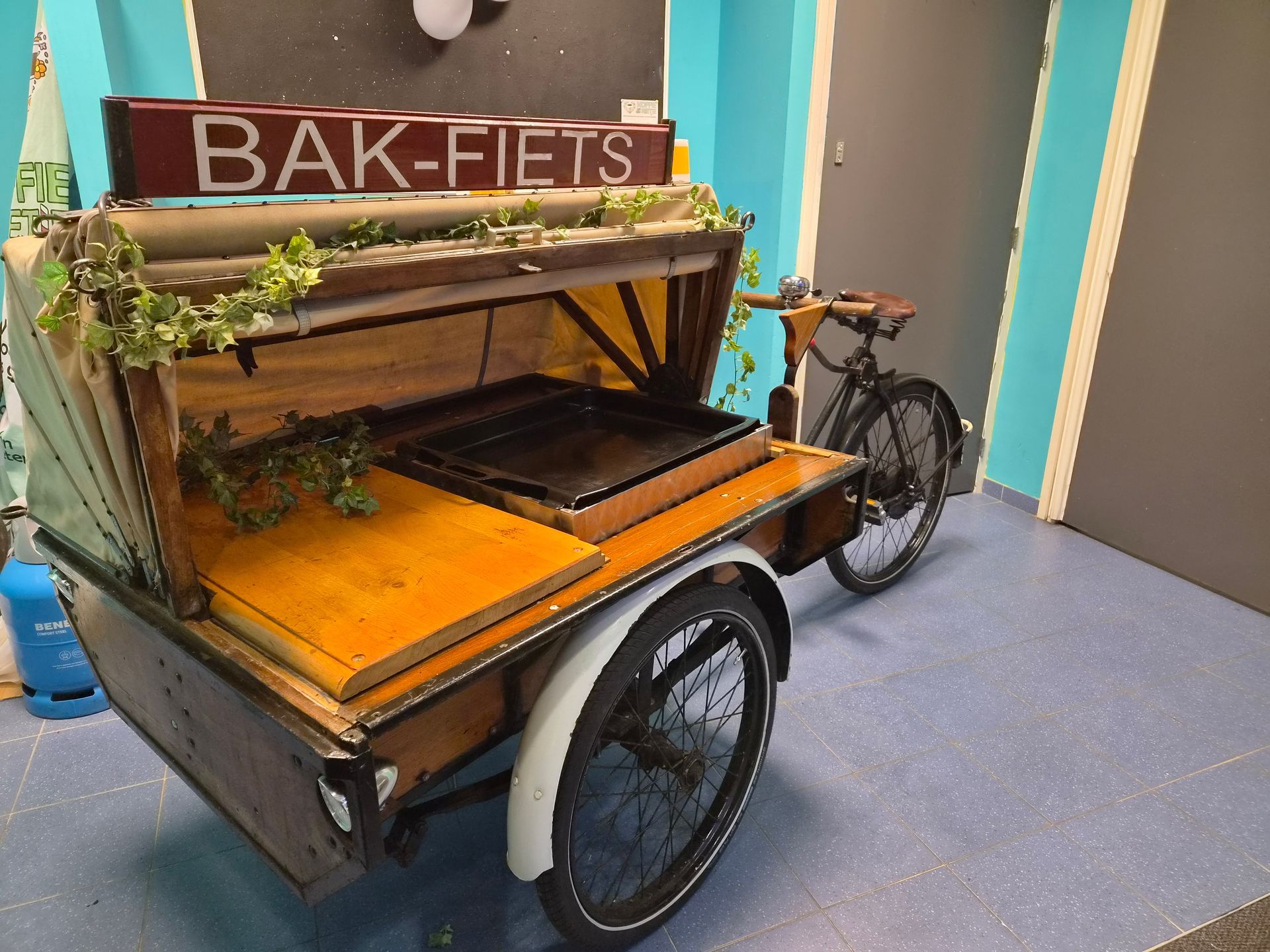 Een houten bakfiets met canvas dak, met het opschrift 