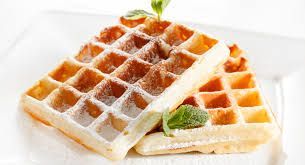 Twee goudbruine wafels, bestrooid met poedersuiker, liggen op een wit bord, gegarneerd met munt.