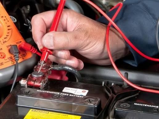 Motor eléctrico sobre una mesa de laboratorio con cables, herramientas y dibujos técnicos al fondo.
