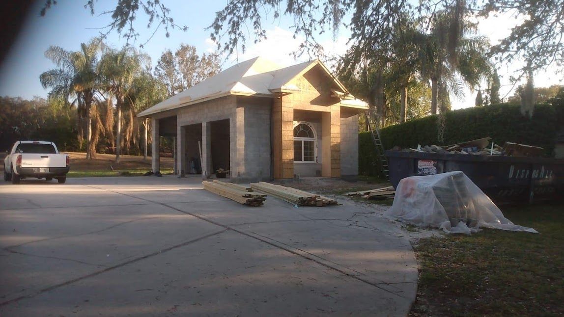 A white truck is parked in front of a garage under construction.