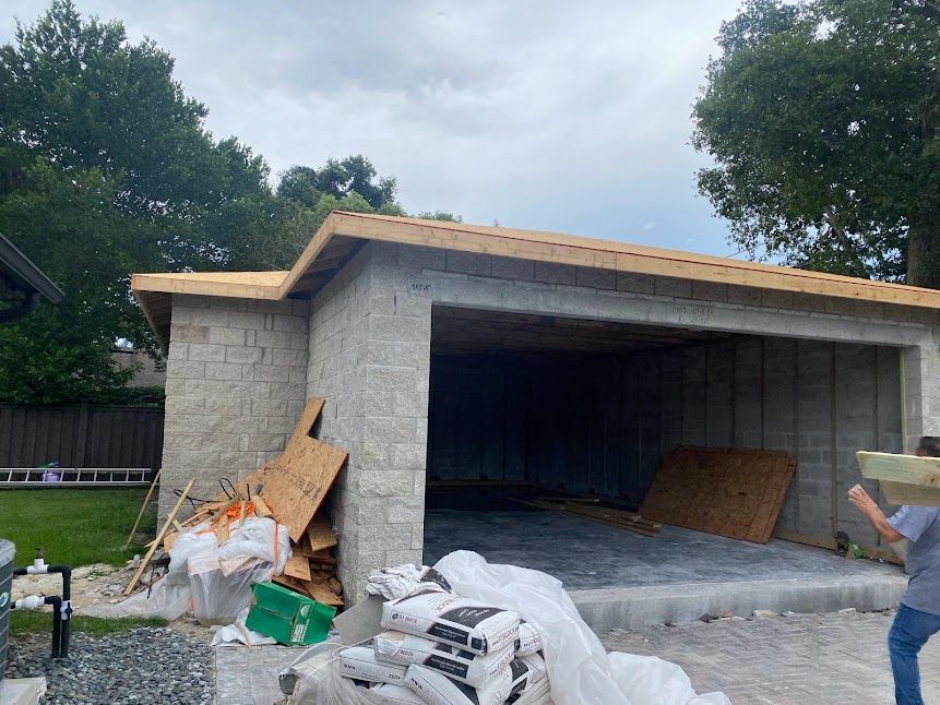 A man is standing in front of a garage under construction.