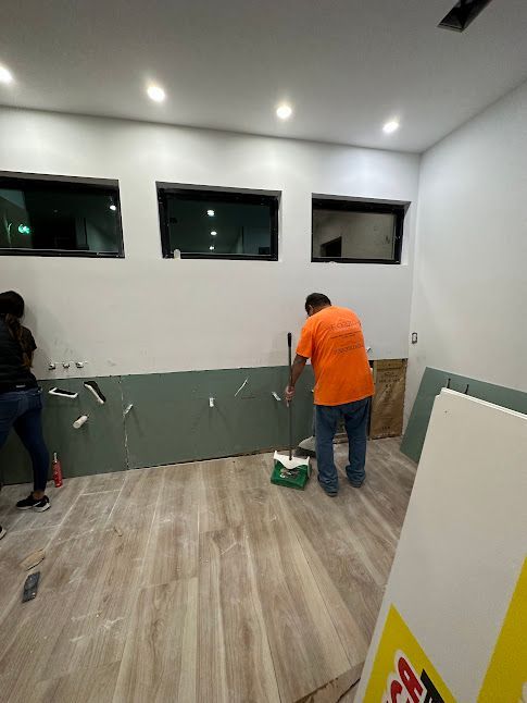 A man is standing in a room with a broom.
