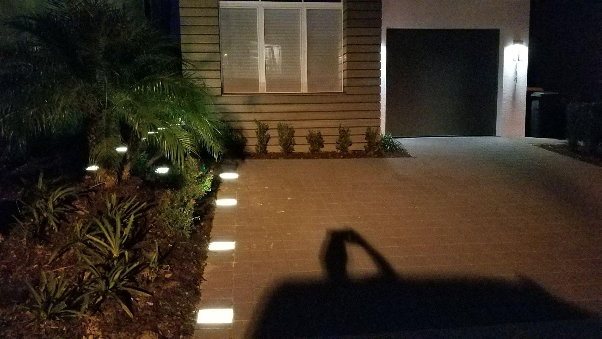A house with a driveway and a garage is lit up at night.