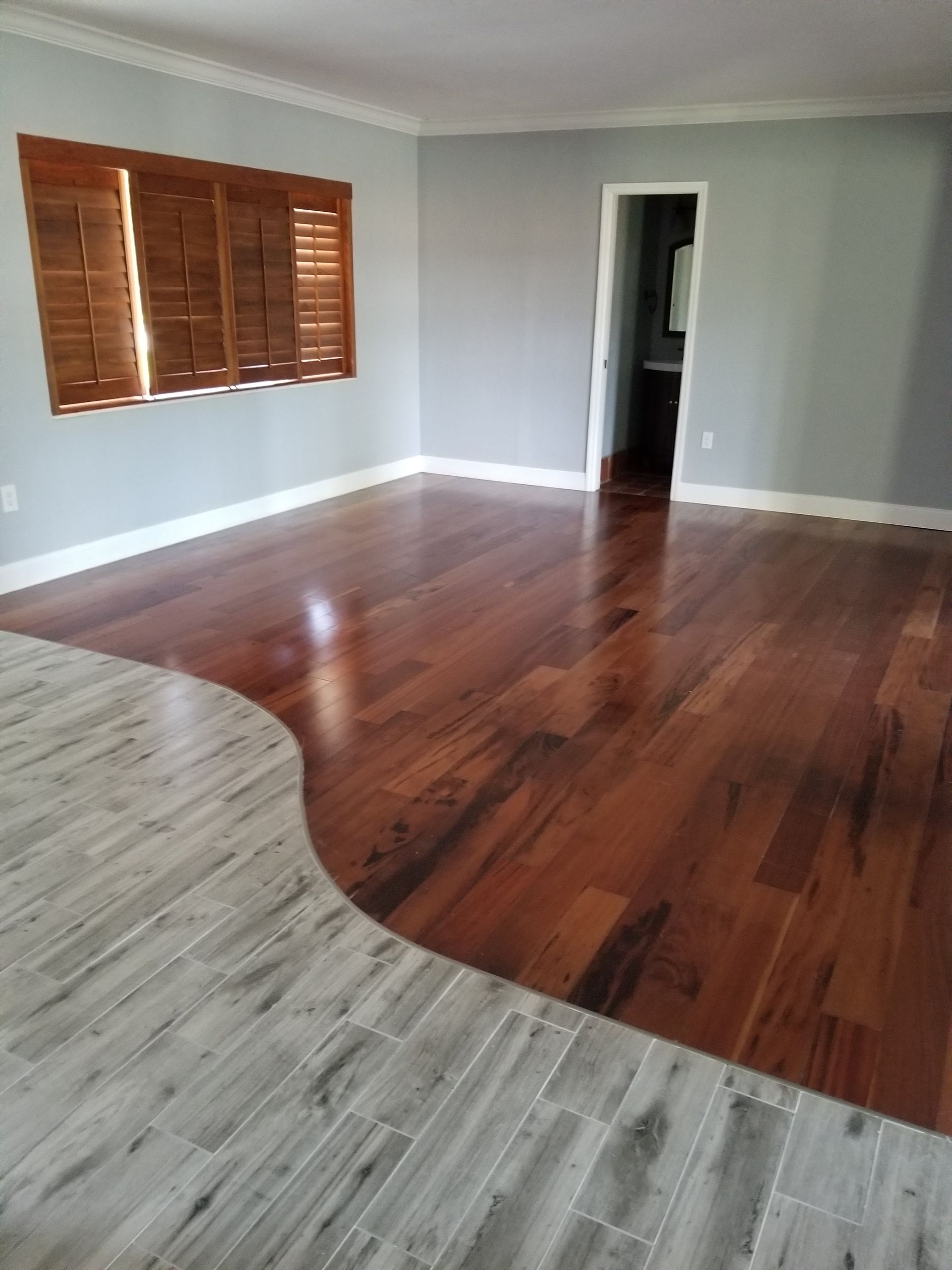A living room with hardwood floors and shutters on the windows.