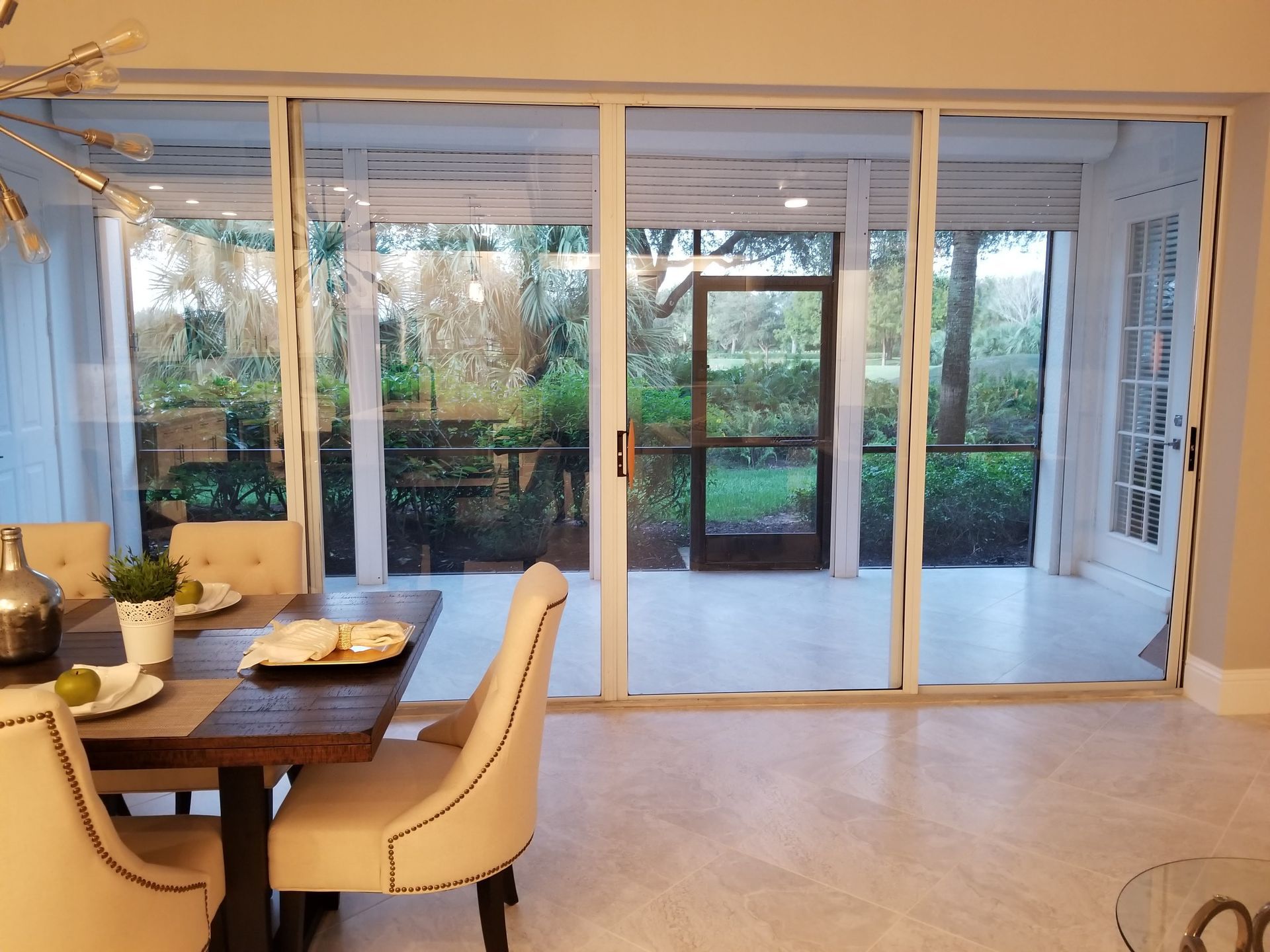 A dining room with a table and chairs and a screened in porch