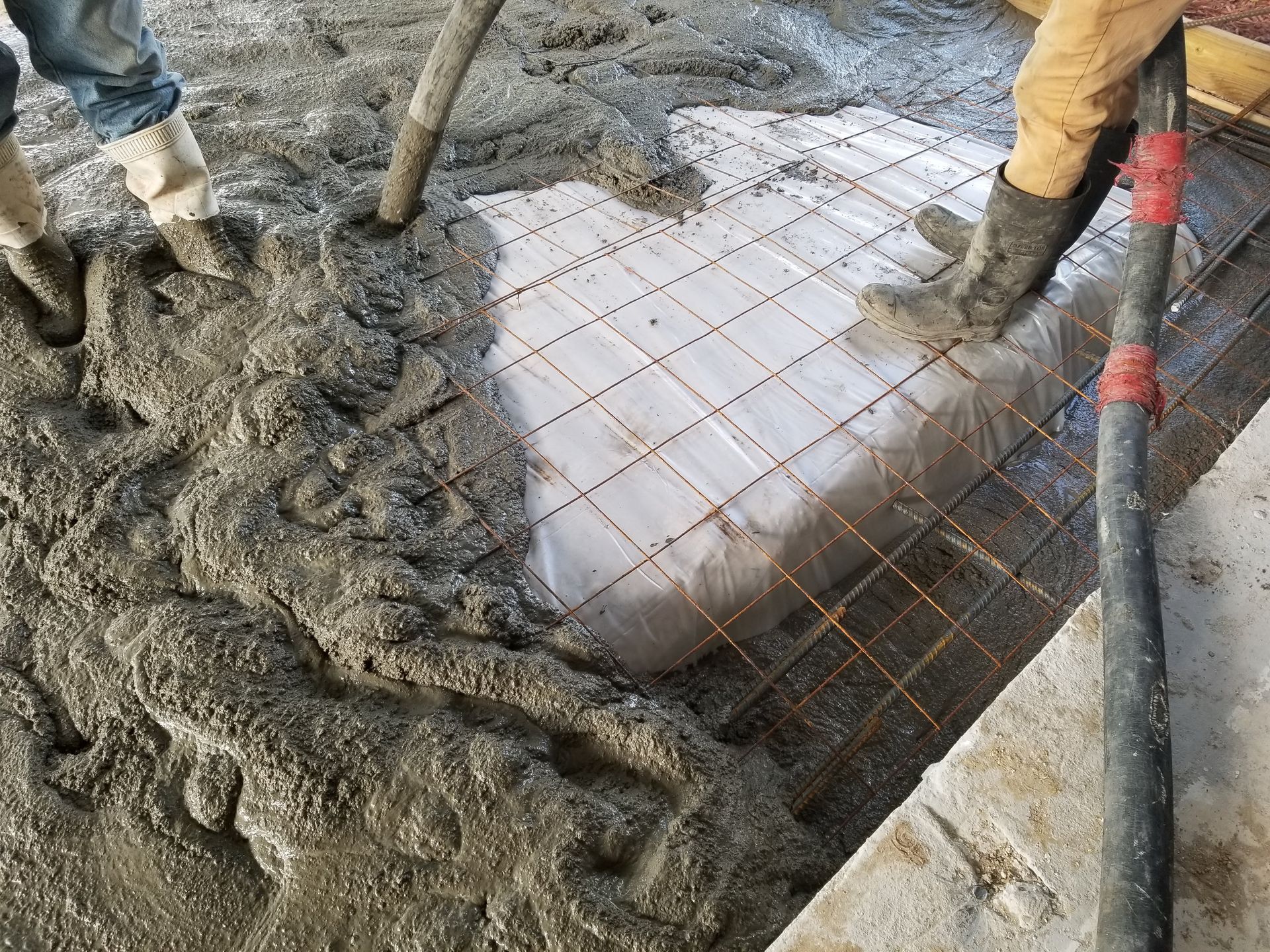 A person is pouring concrete into a hole in the ground.