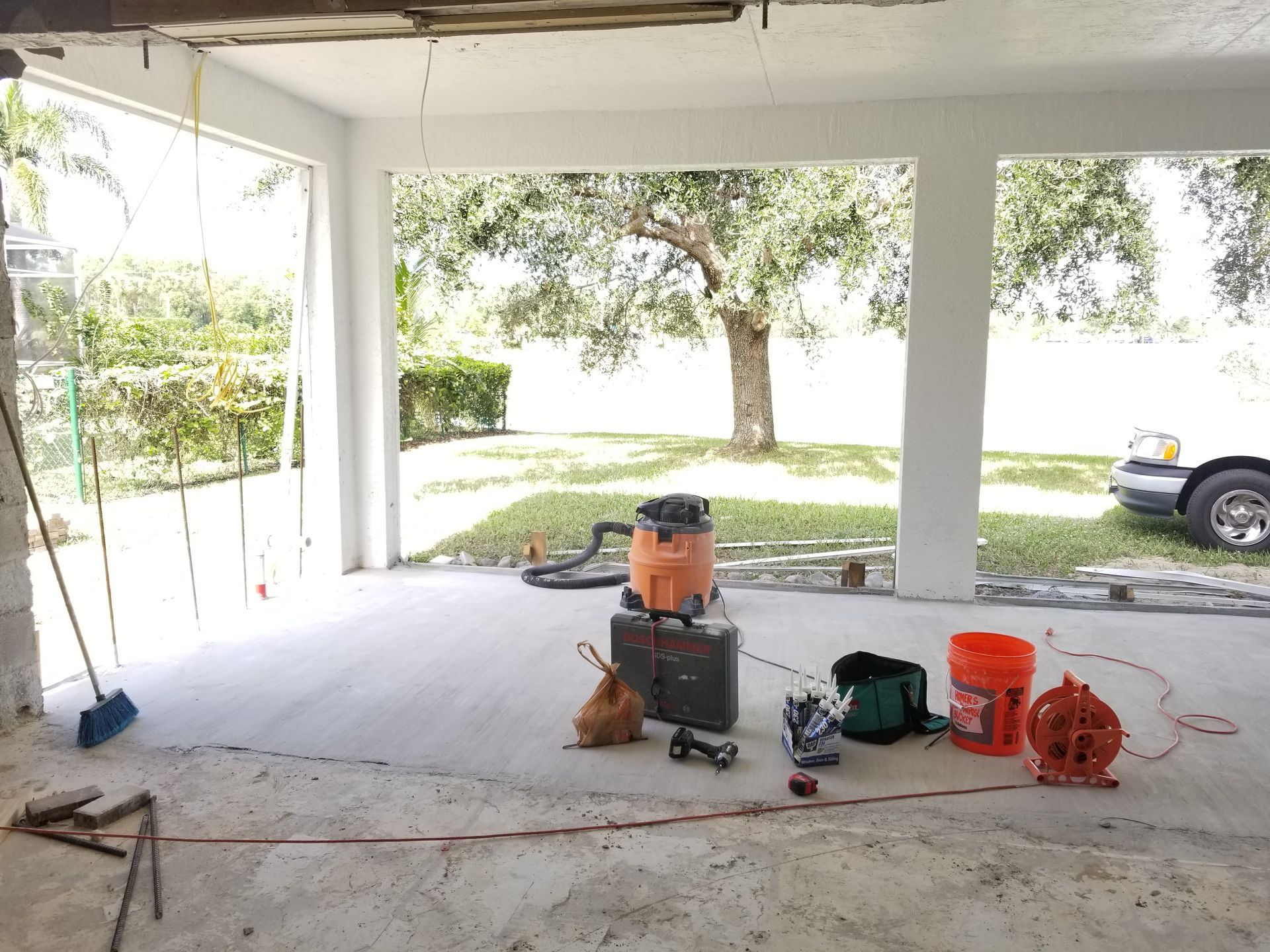 A garage with a vacuum cleaner and tools on the floor