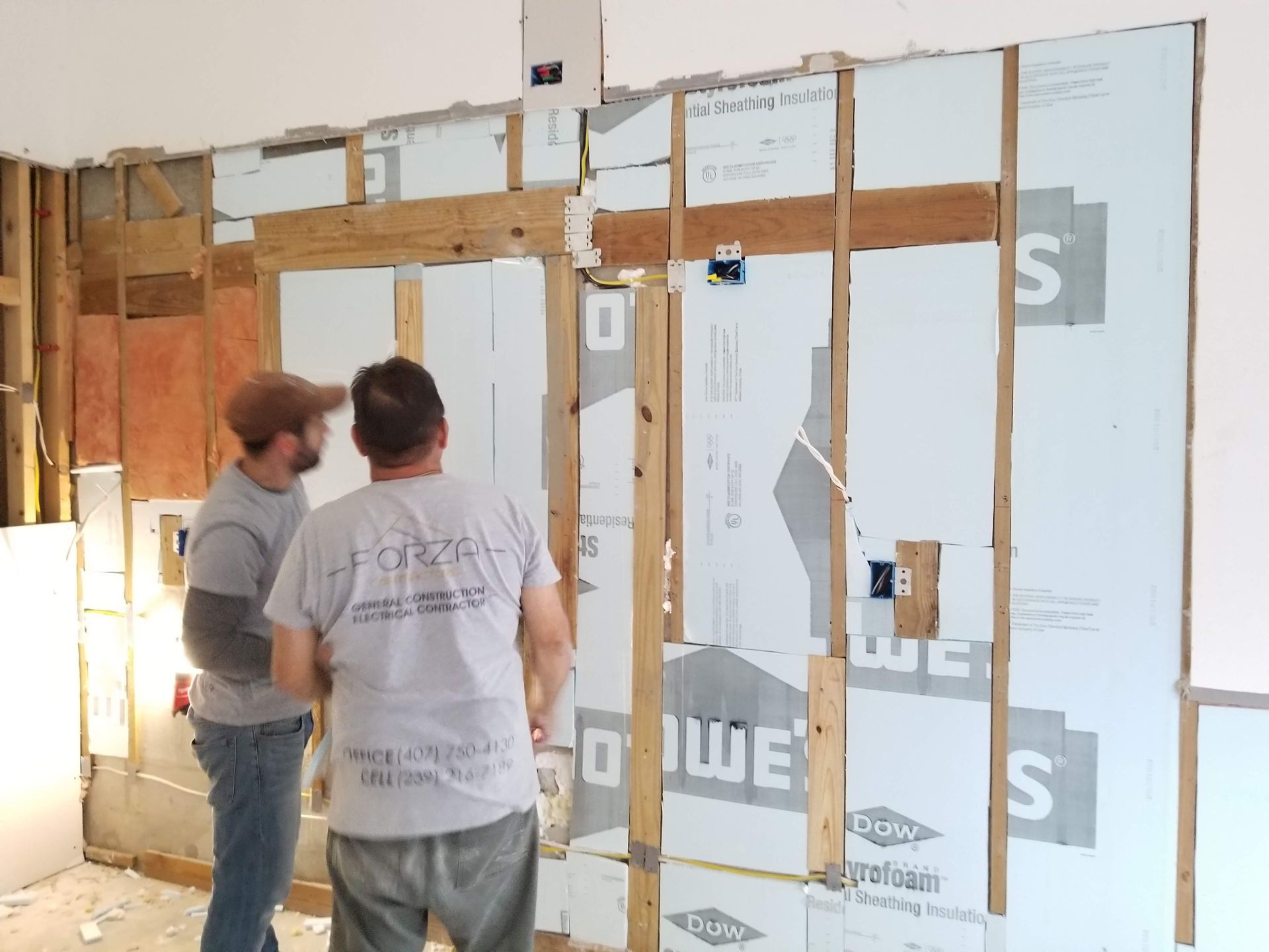Two men are standing in front of a wall that says ' s ' on it