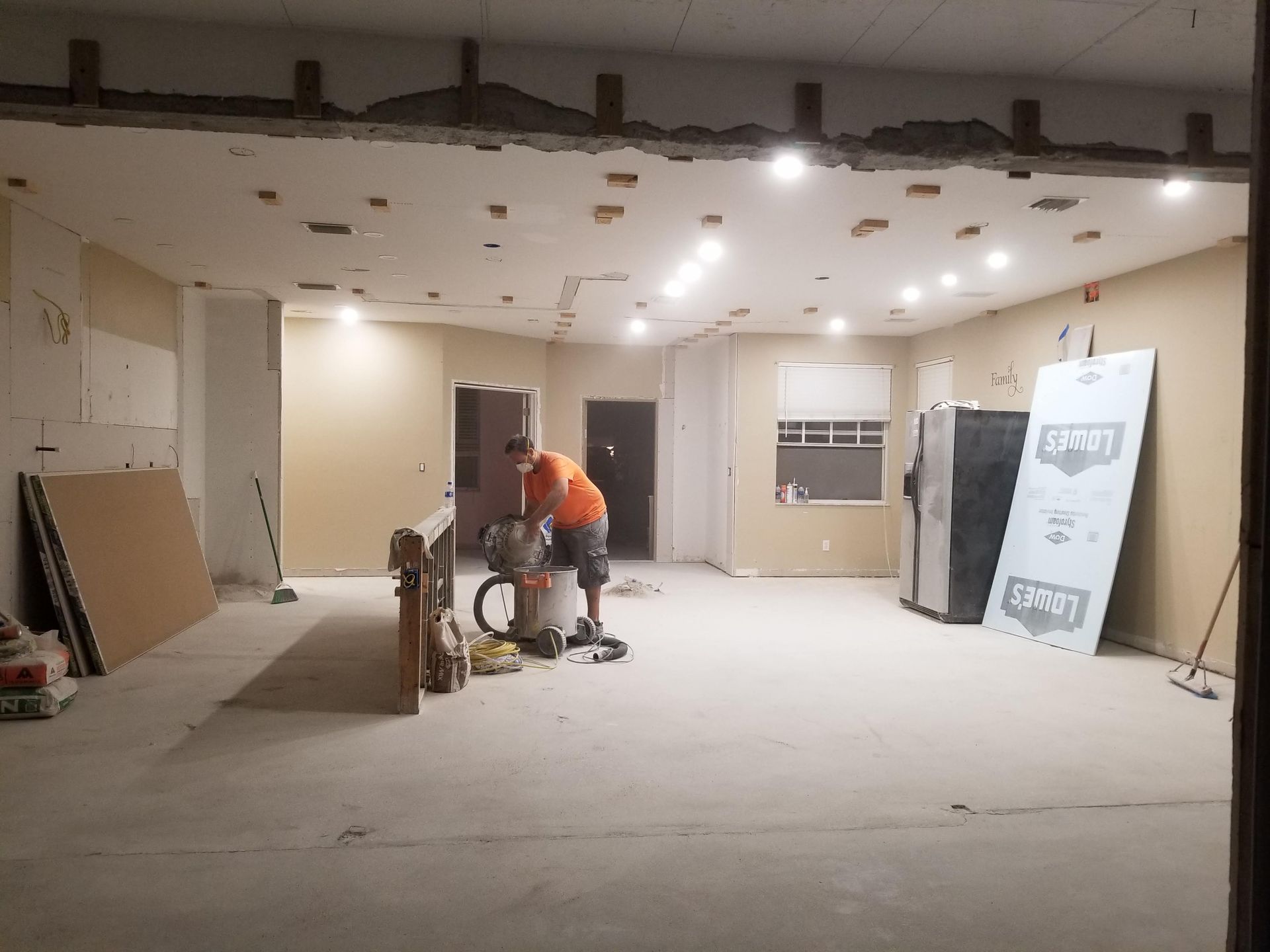 A man is working in an empty room with a vacuum cleaner.