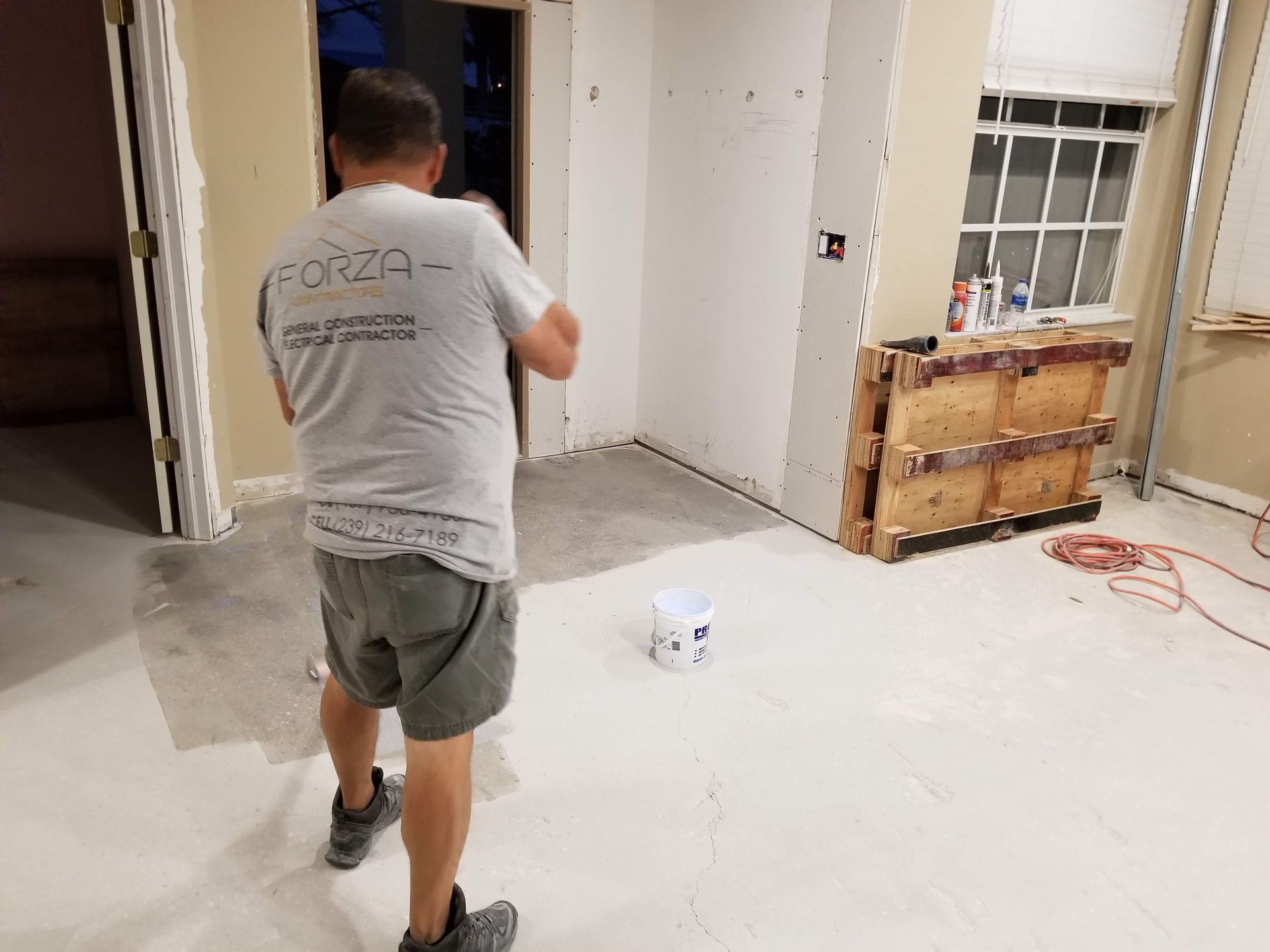 A man in a gray shirt is standing in a room.