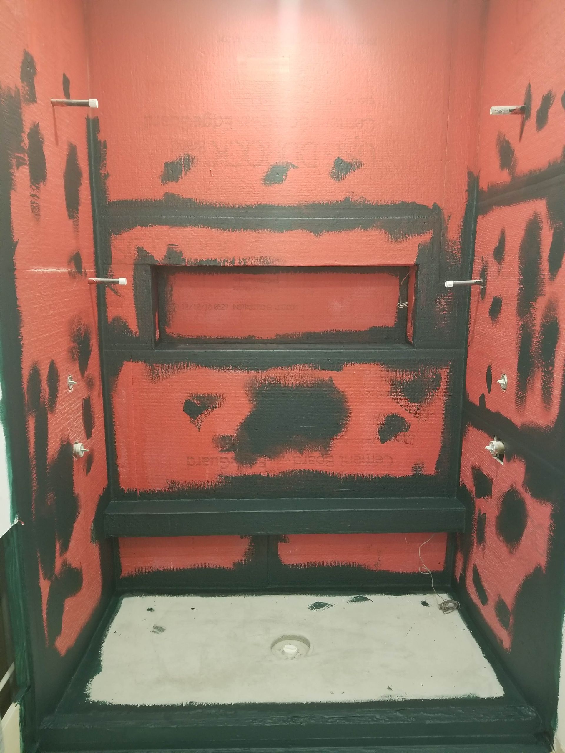A bathroom with red walls and black shelves.