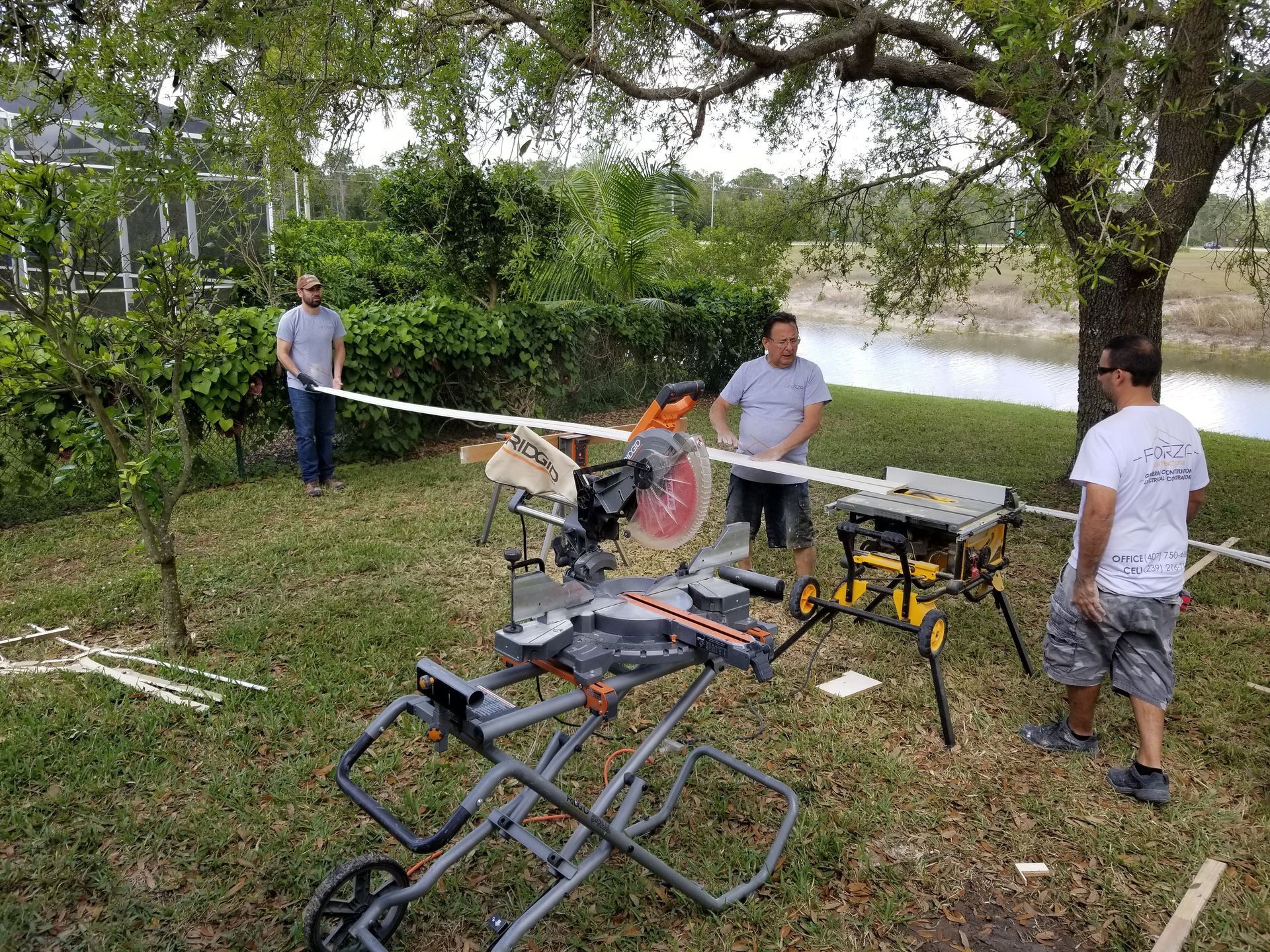 Two men are standing next to a circular saw in a yard.