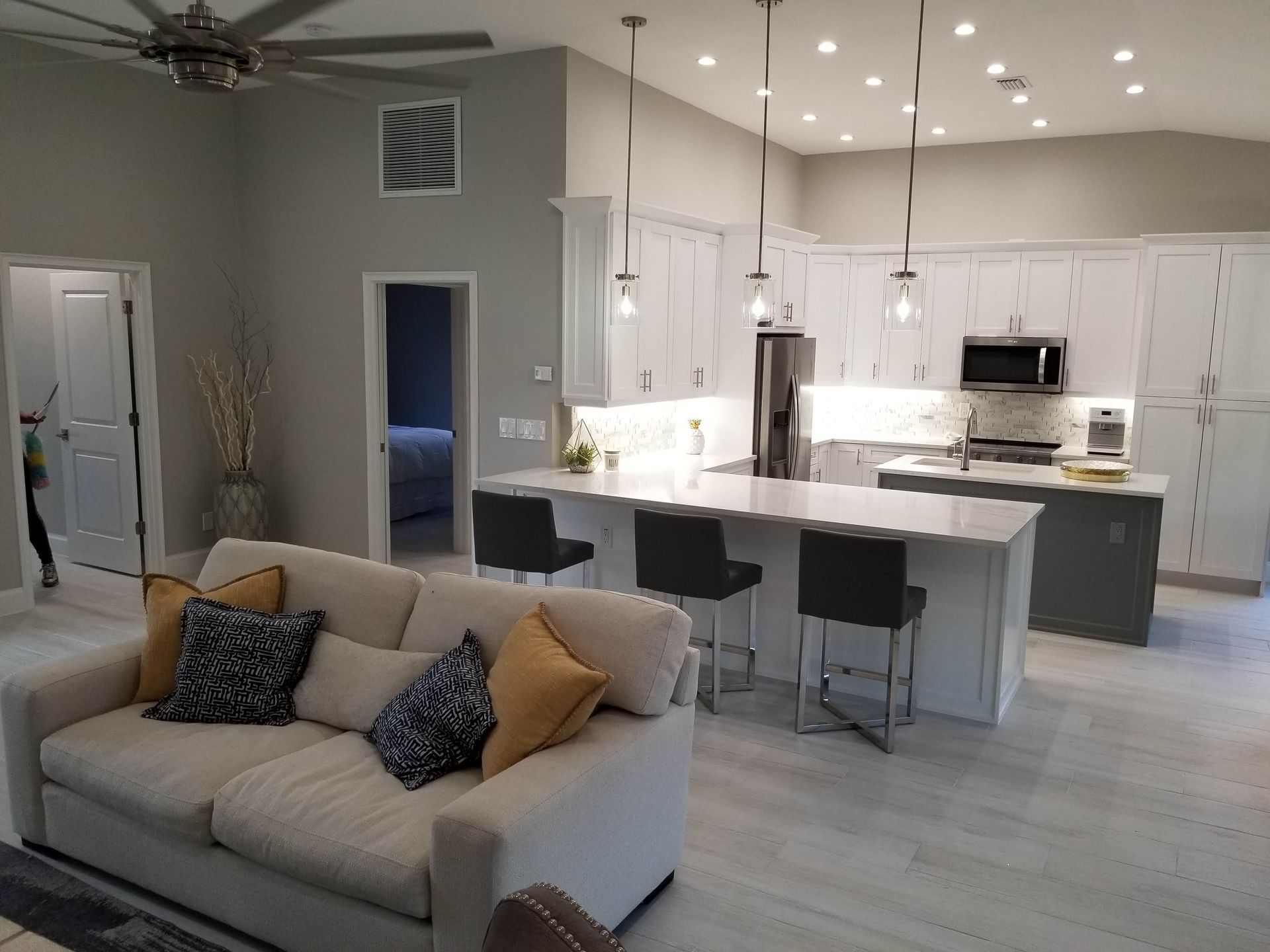 A living room with a couch and a kitchen in the background.