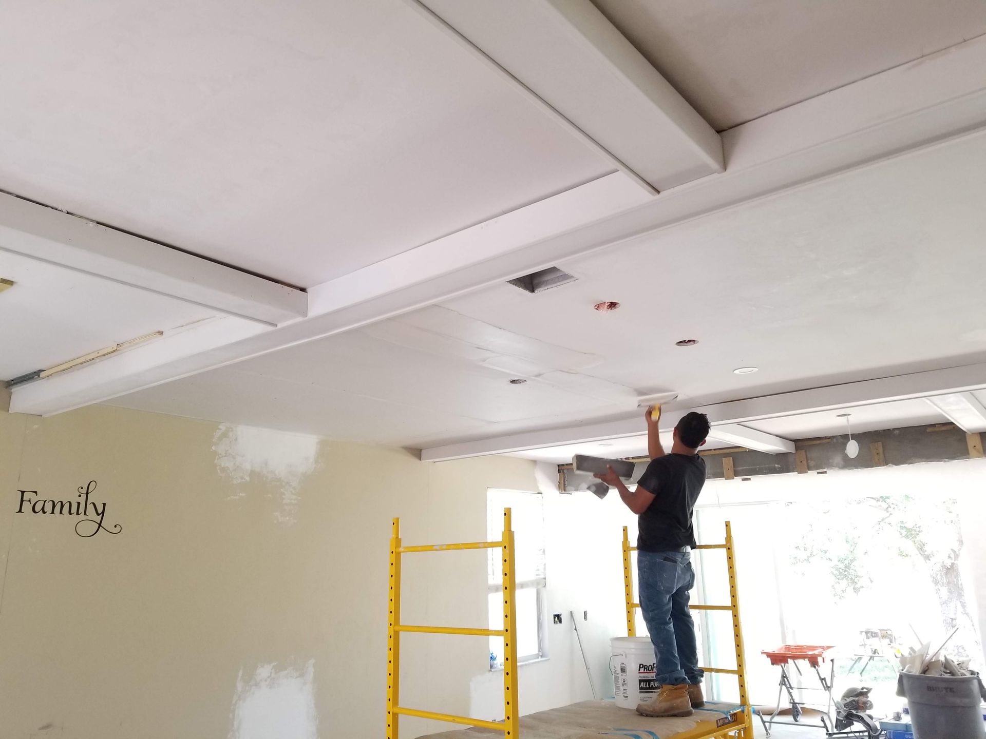 A man is standing on a scaffolding working on a ceiling ..