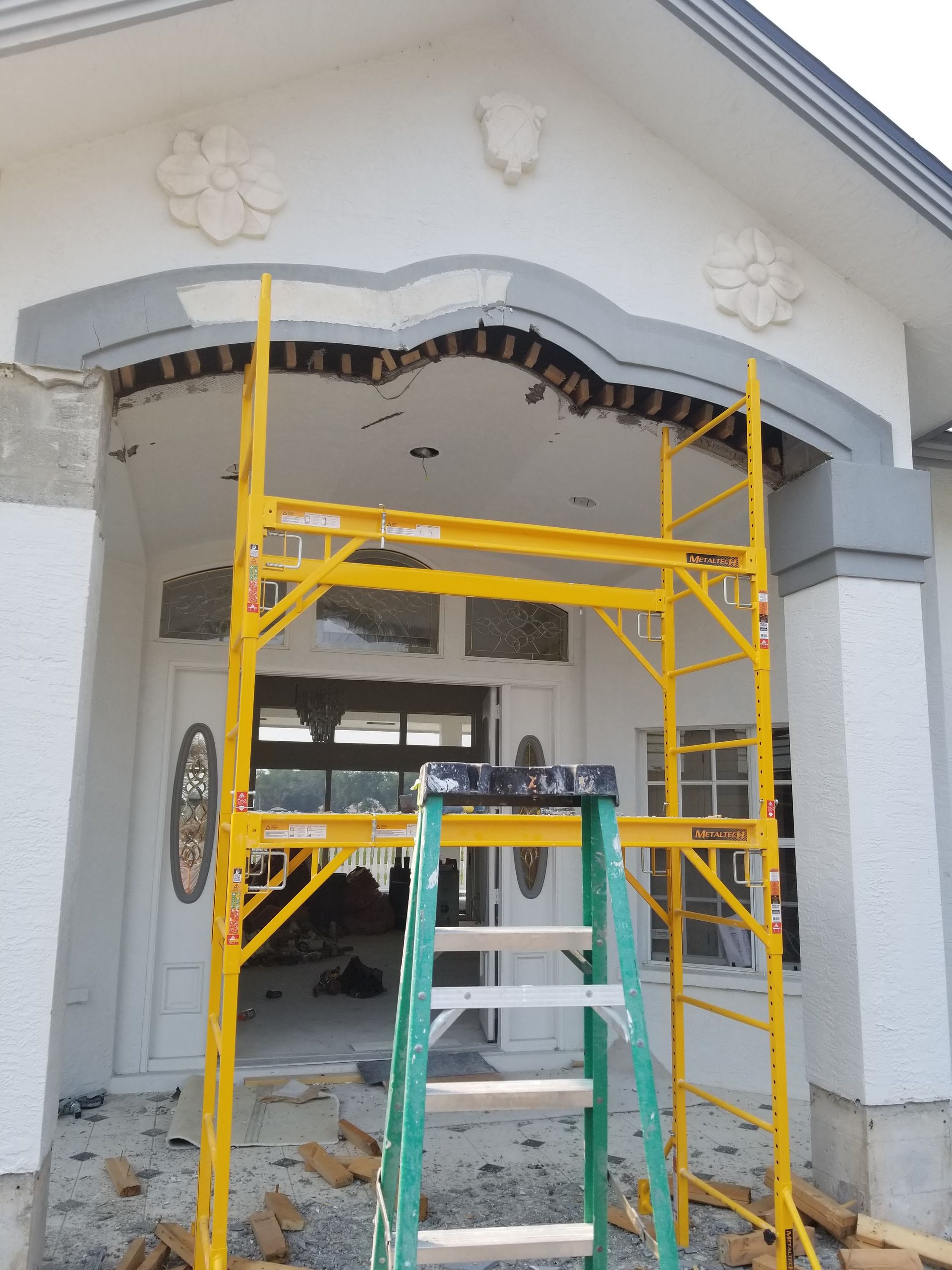 A ladder is sitting on a yellow scaffolding in front of a house